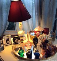 Overall view of the vintage perfume bottles and vanity items on brass and mirror trays with lamp in background