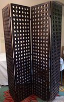 View of entire 4-panel wooden folding screen standing upright with visible star-shaped cutout pattern on each panel.