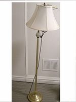 Full view of the brass floor lamp with white shade and visible power cord.