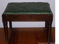 Front view of vintage solid wood foot stool with green cushioned seat showing condition and design details