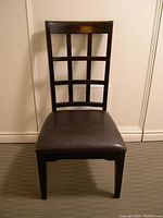 Four solid wood chairs with padded seats, dark finish, and grid design on high backs.