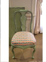 Front view of one green wooden French Provincial style chair with upholstered seat in orange and teal geometric fabric, showing carved cabriole legs and decorative backrest design.