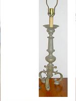 Front view of the vintage metal lamp base showing the detailed metalwork, baluster form central column, and ornate tripod legs, without shade or bulb.
