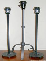 Three metal Ikea table lamps standing upright with sockets visible, no shades or bulbs attached