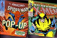Photo showing two Marvel pop-up books: 'The Amazing Spider-Man Pop-Up' and 'X-Men Pop-Up'. Both have colorful front covers featuring Marvel superheroes.
