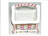 Topdown view of the ceramic gingerbread house basket showing the candy cane striped handle, white roof edges, window decorations, and colorful candy details at the base