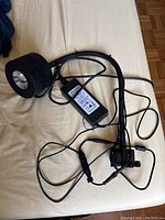 Black aquarium light with a flexible gooseneck and clamp mount, along with power adapter and connected cords spread on a light-colored fabric.