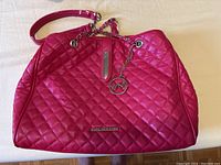Front view of pink quilted purse showing Marc New York metal logo, chain detail handle and zipper closure