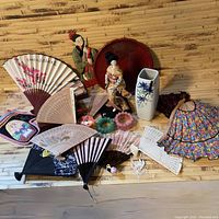 Full overview of the Asian themed items including fans, figurines, vase, and bracelets on bamboo background