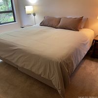 Fully made adjustable bed with beige bedding and pillows