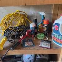 Yellow extension cord and black cord coiled, shop light yellow handle seen along with various spray cans and cleaning products including Hoover SteamVac container.