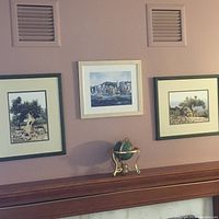 Photo of three framed art prints on wall and small decorative globe on mantel