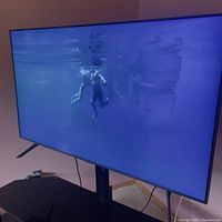 Front view of 55-inch Samsung QLED TV powered on showing screen and stand