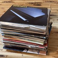 Stack of vinyl records with David Foster album on top, showing album art of a piano keyboard and black background.