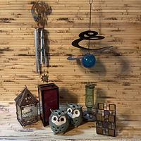 Full view of lot items showing wind chime, hanging blue glass orb, ceramic owl holders, candle holders, bird feeder, and mosaic tile.