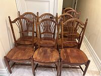 Front view of all eight chairs showing the two armchairs on the ends and six side chairs in between.