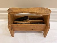 Wooden shoe shining stand holding four brushes