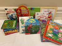 Full lot of 14 children's board books with colorful covers including educational titles and popular characters, arranged on the floor.