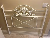 Front view showing the overall structure, white painted metal, and decorative design of birds and floral bouquet.