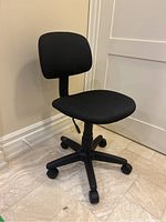 Front angle showing black fabric swivel office chair with padded backrest and seat, height adjustment lever, caster wheel base.