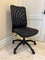 Side view of black mesh back office chair with fabric seat, showing the overall structure, seat, backrest, base, and caster wheels.