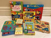 Image showing the collection of children's puzzles and educational books including Let's Count, Thomas & Friends puzzles, My Colors book, Animal Match puzzle, and two wooden puzzles.