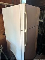 Full side angle view of the white refrigerator showing the shape and condition.
