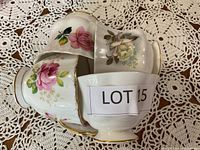Four bone china cups stacked with floral patterns and LOT 15 label visible.