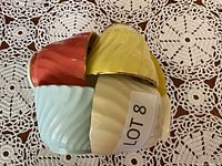 Image of four stacked bone china cups in pastel colors: red, light blue, yellow, and cream, showing their exterior swirled design.