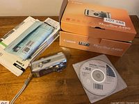 Canon PowerShot A460 camera, manuals, installation software disc, and original box displayed on wooden surface.