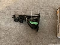 Set of cast iron plant hangers bundled together, showing their curled hook ends and mounting plates, some with black paint wear and rust spots.