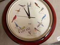 Front view of Ergo Quartz clock showing bird illustrations for each hour and black clock hands.