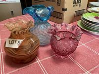 Three decorative glass vases on red check tablecloth: brown swirled, pink with starburst pattern, and blue with diamond pattern.