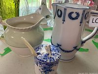 Three small decorative serving pieces: creamer, mustard pot with spoon, and decorated mug.