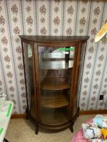 Front view of the demi-lune china cabinet showing curved glass, wooden frame, and interior shelves.