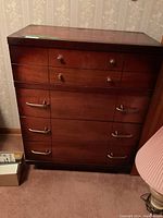 Full view of the wooden dresser showing the top surface, drawer arrangement, and varied handles.