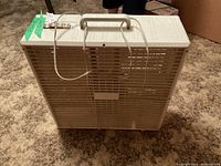 Photo of the white plastic box fan front, showing the vented panel for airflow.