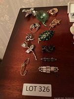 Lot of 11 assorted jewelry pins with floral and abstract designs collected on wooden surface.