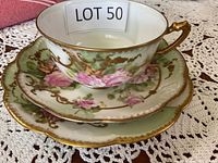 Bone china tea cup stacked on saucer and plate with floral and gold decoration.