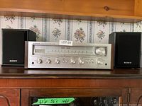 Front view of the Pioneer receiver between two Sony speakers on a wooden shelf.