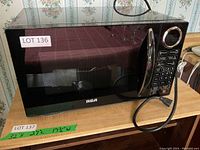 Front view of the RCA black microwave oven showing the door, keypad controls, and handle.