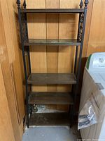 Full front view of the shelving unit showing four wooden shelves and decorative metal sides.