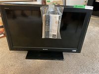 Sony Bravia LCD TV showing front view with remote and manual attached in plastic bag.
