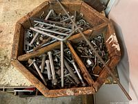 Top and angled view of the vintage wooden sectioned box filled with various metal bolts, nuts, and washers in different compartments.