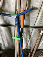 Photo showing blue weed puller, orange handled tool, and wooden handled tool with metal fork