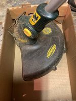 Close-up image of the protective guard section of Yardworks trimmer showing branding and hinge area.