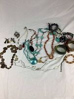 Wide view of the complete lot showing mixed jewelry pieces laid out on white fabric