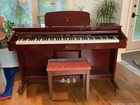 Front view of Kawai digital piano and bench showing keyboard, control buttons, pedals, and overall condition with some wear visible on bench.
