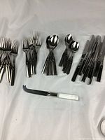 Wide view showing grouped forks, spoons, knives, and an additional knife with white handle.