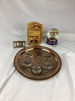 Wide view of all four items: metal Passover plate, brass menorah, wooden box, and Menorah snow globe.